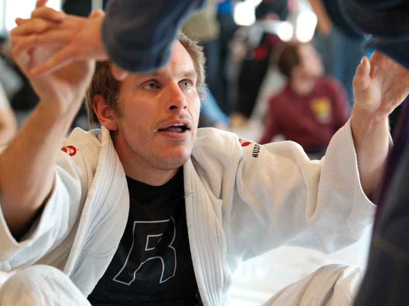 Novus Academy Molde BJJ-utøver i gi som forbereder seg på å gripe fra sittende guard